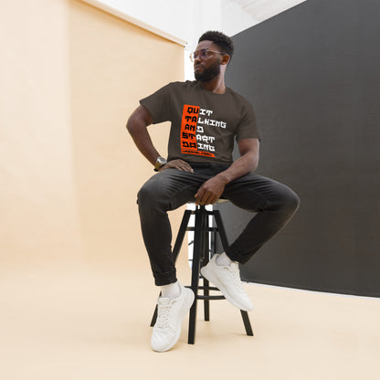 Man sitting on a stool wearing a t-shirt with text, against a plain background